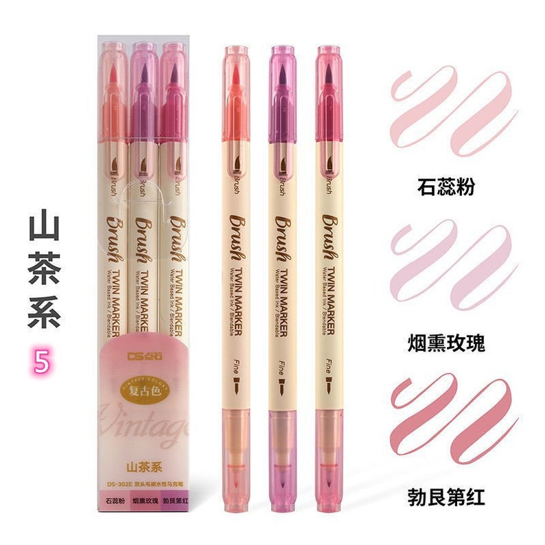 May include: A set of five dual-tip brush markers in shades of pink and peach. The markers are labeled "Brush Twin Marker" and "Fine". The packaging includes the text "Vintage" and Chinese characters. Swatches of the marker colors are displayed.