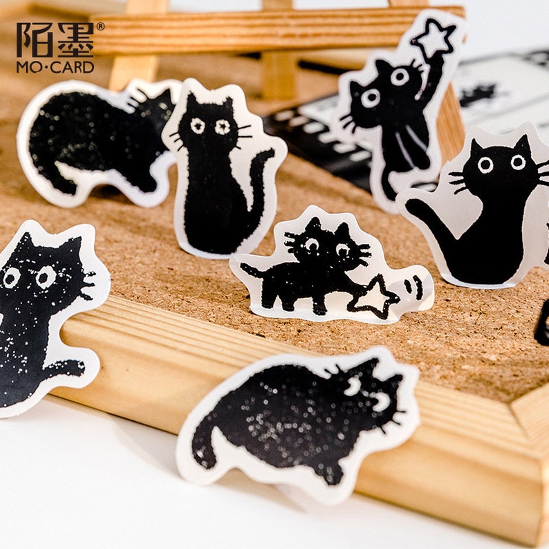 May include: A set of black and white cat stickers with various poses. The stickers feature a simple, minimalist design with a textured, hand-drawn look. The stickers are perfect for adding a touch of whimsy to journals, planners, and other craft projects.
