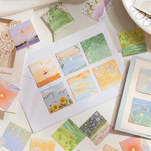 May include: A set of 10 colorful square stickers featuring various nature scenes. The stickers are printed with watercolor-like illustrations of flowers, clouds, and landscapes.