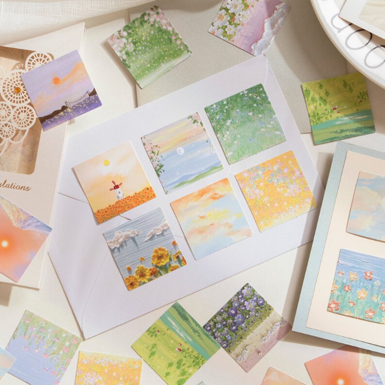 May include: A set of 10 colorful square stickers featuring various nature scenes. The stickers are printed with watercolor-like illustrations of flowers, clouds, and landscapes.