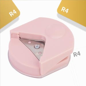 K&ouml;nnte beinhalten: Ein rosa Eckrundungswerkzeug mit einer Metallklinge. Das Werkzeug wird verwendet, um die Ecken von Papier zu runden.