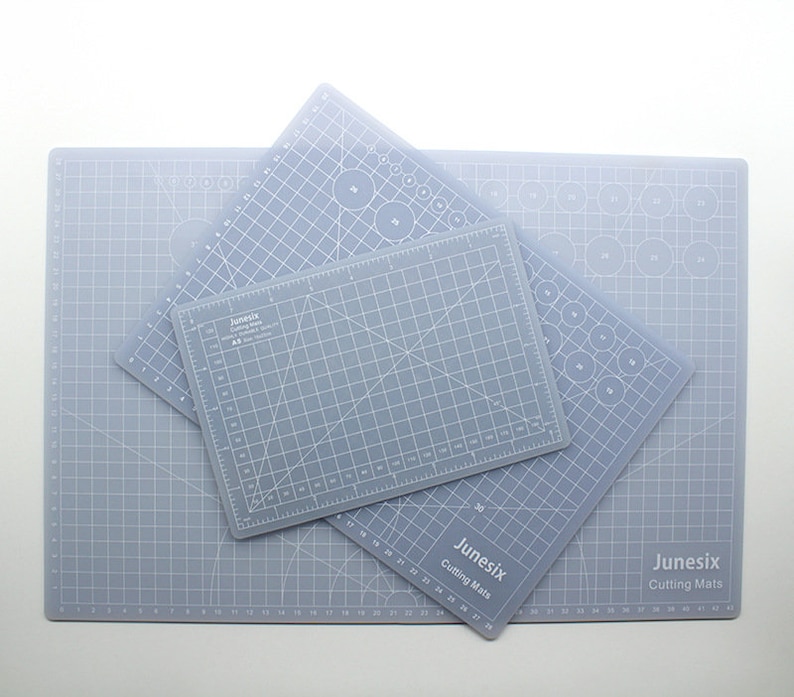 K&ouml;nnte beinhalten: Drei graue, selbstheilende Schneidematten mit Gitterlinien und Kreisen. Die Matten sind mit "Junesix Cutting Mats" beschriftet und haben unterschiedliche Gr&ouml;&szlig;en.