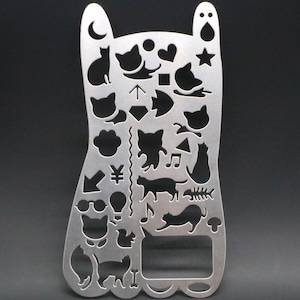 May include: A silver metal stencil with a cat theme. The stencil features various cat silhouettes, paw prints, hearts, stars, musical notes, and other designs.