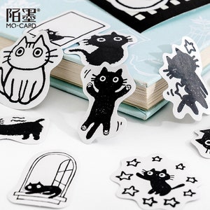 May include: A set of black and white cat stickers with various poses, including a cat sitting, a cat jumping, and a cat looking out a window. The stickers are on a white background and have a simple, minimalist design.