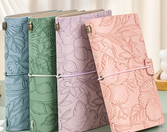 May include: Four leather-bound journals with floral embossed designs. The journals are in shades of blue, green, purple, and pink.
