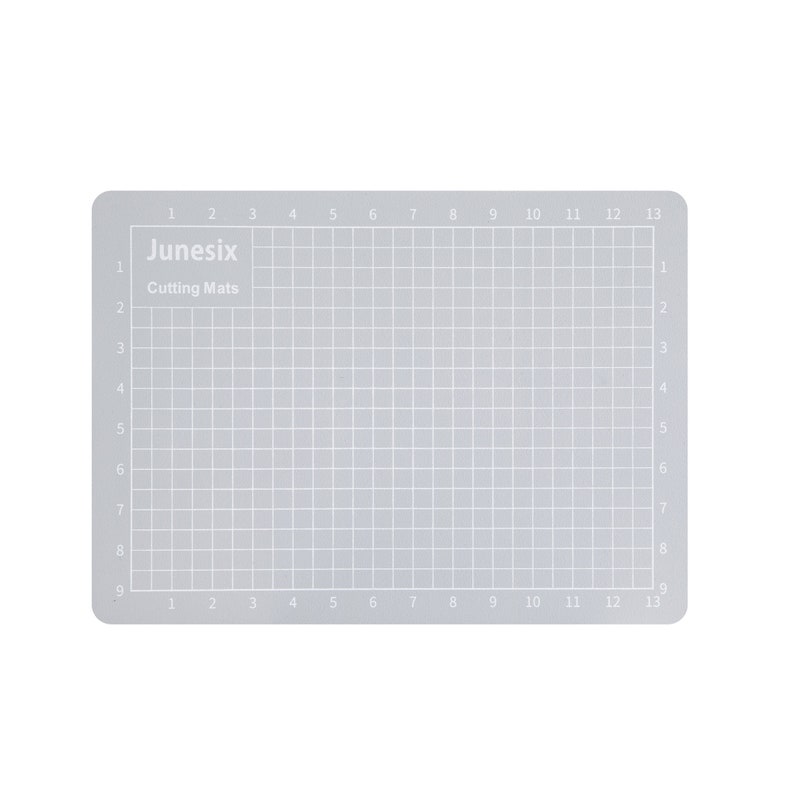 May include: A gray self-healing cutting mat with a grid pattern and numbers 1 through 13 along the top and bottom edges. The mat is labeled "Junesix Cutting Mats".