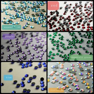 May include: A collection of small, round, faceted rhinestones in six distinct color groups: aquamarine AB, red, purple, emerald green, blue, and crystals AB. Each section features loose, flat-backed stones scattered across a neutral surface.