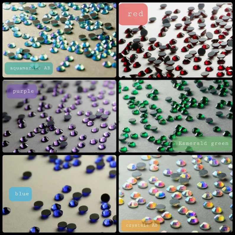 May include: A collection of small, round, faceted rhinestones in six distinct color groups: aquamarine AB, red, purple, emerald green, blue, and crystals AB. Each section features loose, flat-backed stones scattered across a neutral surface.