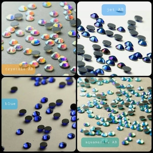 May include: A collection of small, round, faceted rhinestones in four distinct color variations: iridescent crystals AB, dark jet AB, solid blue, and light aquamarine AB. Each stone features a flat, textured back for adhesive application.