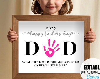 May include: A framed print with the word "DAD" in large black letters, a pink handprint, and the text "Happy Fathers Day 2025". The print also includes the quote, "A father's love is forever imprinted on his child's heart."
