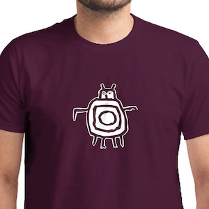 May include: A maroon t-shirt with a white graphic of a stylized creature with a circle in the middle.