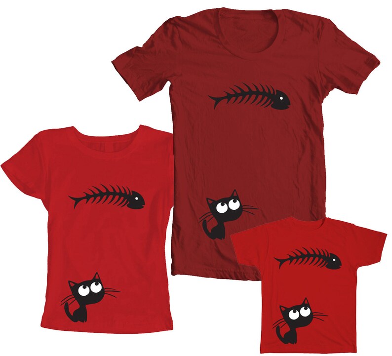 May include: Three red t-shirts with a black cat and fishbone design. The largest shirt has a fishbone on the front and a cat looking up at it. The medium shirt has a cat looking up at a fishbone on the front. The smallest shirt has a cat looking up at a fishbone on the front.