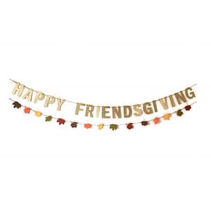 Może przedstawiać: Złota girlanda z błyszczącymi literami z napisem "Happy Friendsgiving" przewleczona na sznurku z małymi papierowymi liśćmi w odcieniach pomarańczowego, ż&oacute;łtego, czerwonego i brązowego.