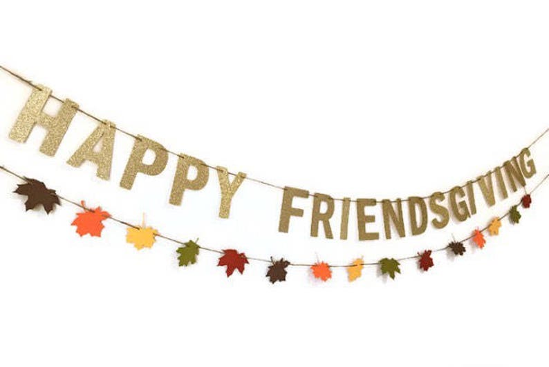 Może przedstawiać: Złota girlanda z błyszczącymi literami z napisem "Happy Friendsgiving" i ozdobami w kształcie jesiennych liści.