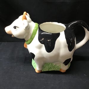 VTG Glazed Ceramic Cow Creamer Pitcher. Holstein Cow w/Bell Laying In The Grass.  Farmhouse Decor. Wang’s International, Inc.