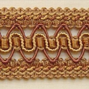 May include: A close-up of brown and gold trim with a woven design. The trim has a scalloped edge and a repeating pattern of small loops.