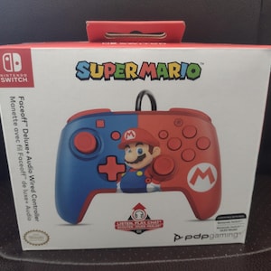 May include: A red and blue wired controller for the Nintendo Switch with a Super Mario theme. The controller features a Mario character design and the text "Super Mario" on the packaging.