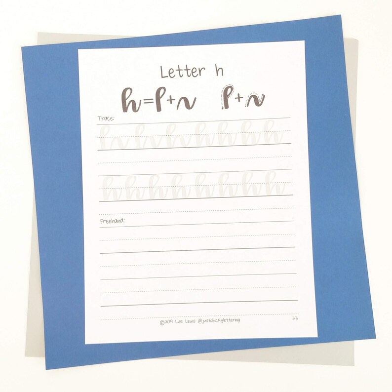 May include: A white paper with calligraphy practice for the letter "h" is displayed on a blue background. The paper includes the letter "h" broken down into strokes, with tracing and freehand sections. The text "Letter h" is at the top.