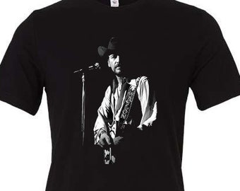 May include: Black t-shirt with a white silhouette of a country music singer holding a guitar and wearing a cowboy hat.