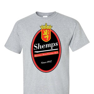 Könnte beinhalten: Ein graues T-Shirt mit einem schwarzen und roten Logo, auf dem "Shemps" steht, sowie dem Text "America's Finest Premium Beer" und "Since 1937" darunter.