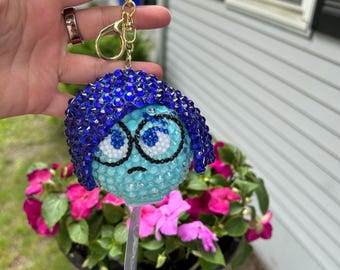 Diadema de peluche y llavero inspirados en Tristeza de Inside Out, con incrustaciones de pedrería.