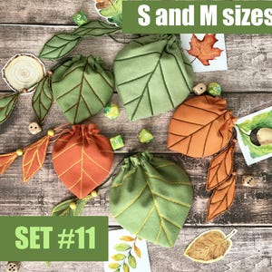 May include: A collection of leaf-shaped drawstring bags in green and orange, with matching leaf embellishments. The bags are in S and M sizes, with the text "SET #11" visible. Dice and decorative leaf accents are also present.