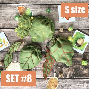 May include: Green leaf-shaped dice bags with yellow and red stitching, and drawstring closures. The bags are labeled "S size" and "SET #8". The image includes dice and leaf-themed artwork on a wooden surface.