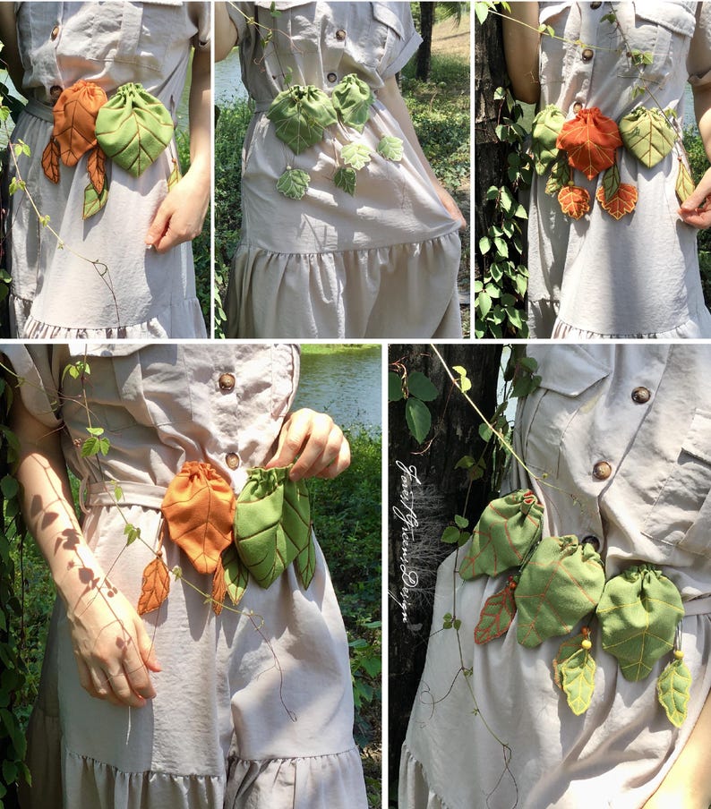 May include: A beige dress with a leaf-themed accessory. The accessory features green and orange leaf-shaped pouches and leaves, connected by a vine. The dress has a button-down design and a ruffled hem.