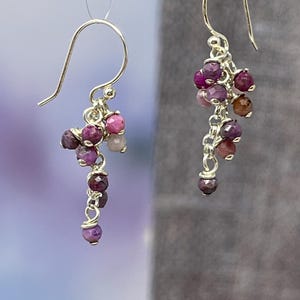 Könnte beinhalten: Ein Paar silberne Ohrhänger mit rosa und violetten Edelsteinperlen.