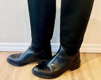 May include: A pair of black leather knee-high boots with a pointed toe and a low heel. The boots are made by the brand "Sudini" and are made in Italy.