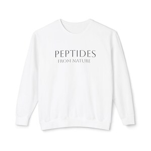 Peut inclure: Sweat-shirt blanc à col rond avec l'inscription noire "PEPTIDES FROM NATURE" centrée sur la poitrine. Le haut à manches longues est fait d'une matière douce.