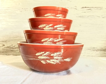 May include: Set of four nesting mixing bowls in a burnt orange colour with a white wheat design.