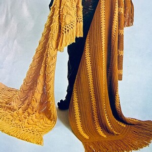 May include: Two crocheted blankets with fringe. One blanket is a golden yellow with a textured pattern and the other is a brown and gold striped pattern.