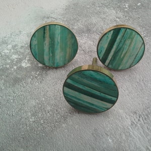 May include: Three round, green and white striped knobs with gold metal trim.