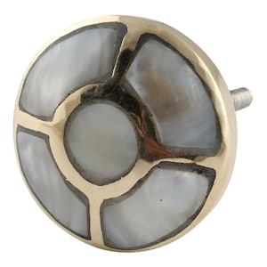 May include: A round brass cabinet knob with a decorative inlay of white mother-of-pearl. The knob has a geometric design with a central circle.