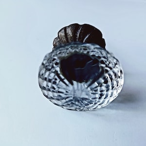 May include: A clear glass door knob with a decorative, textured surface and a metal base.