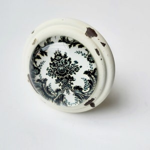 May include: White ceramic knob with a black and white damask pattern. The knob has a distressed finish.