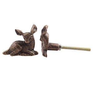 May include: A pair of antique bronze deer drawer pulls with a screw for installation. The deer are in a lying down position.