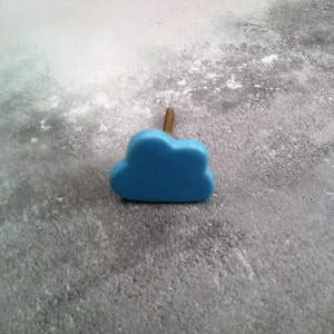 May include: A light blue ceramic cloud-shaped cabinet knob with a gold screw.