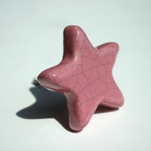 May include: A pink ceramic star-shaped cabinet knob with a crackled glaze finish.