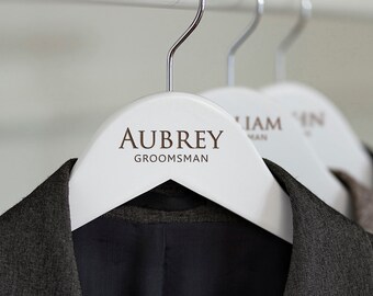 May include: White wooden hanger with the name "Aubrey" and the word "Groomsman" printed in brown text.