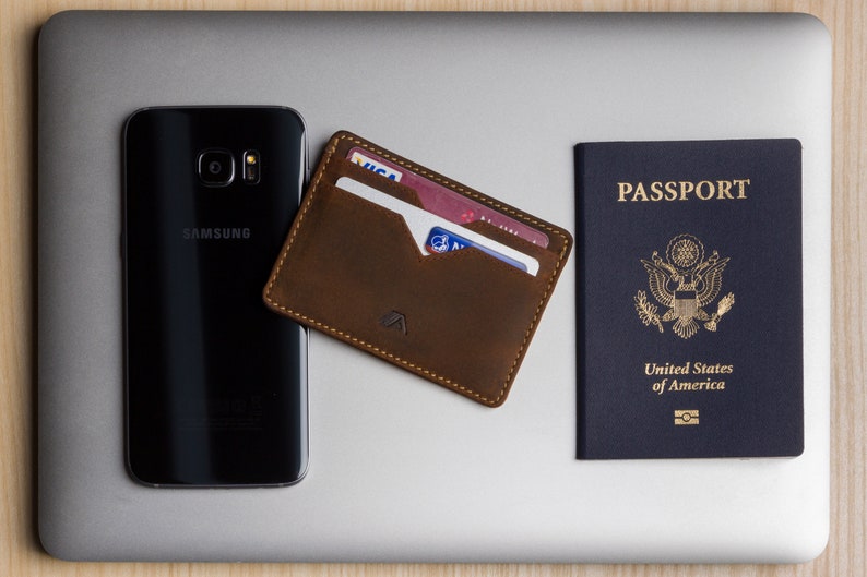 handmade leather card holder lifestyle image on macbook with passport and samsung galaxy phone