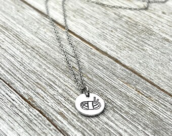 Puede incluir: Un collar de cadena de plata con un colgante redondo que presenta una ilustración en blanco y negro de un rollo de sushi con palillos.