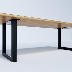 May include: A long, rectangular wooden table with black metal legs. The table top is made of light wood and the legs are square.