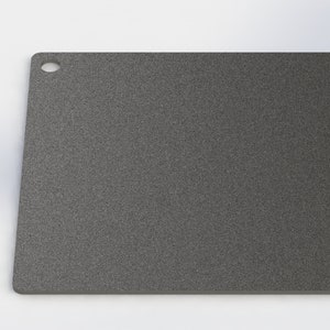 May include: A gray square cutting board with a small hole in the top corner.