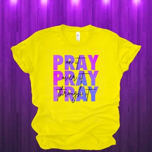 May include: Yellow t-shirt with a purple and blue ombre design that says "Pray on it, Pray over it, Pray through it".