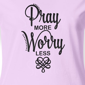 May include: A light purple t-shirt with the text "Pray More Worry Less" in black cursive lettering. A stylized heart design is below the text.