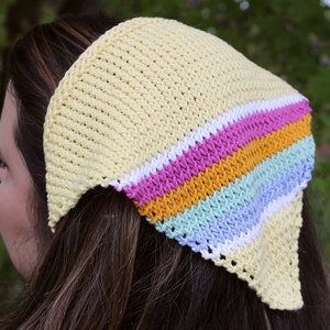 Könnte beinhalten: Ein gelbes gestricktes Stirnband mit einem mehrfarbigen Streifenmuster in Rosa, Orange, Hellblau und Weiß.