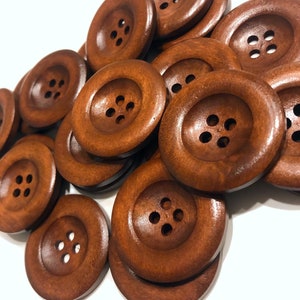 May include: A pile of brown wooden buttons with four holes each. The buttons are arranged in a random pattern and are all the same size.