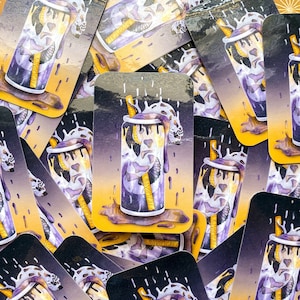May include: A close-up of multiple stickers featuring a purple and yellow can with a straw and a creature inside. The can is surrounded by a purple liquid and yellow drips. The stickers are printed on a white background.